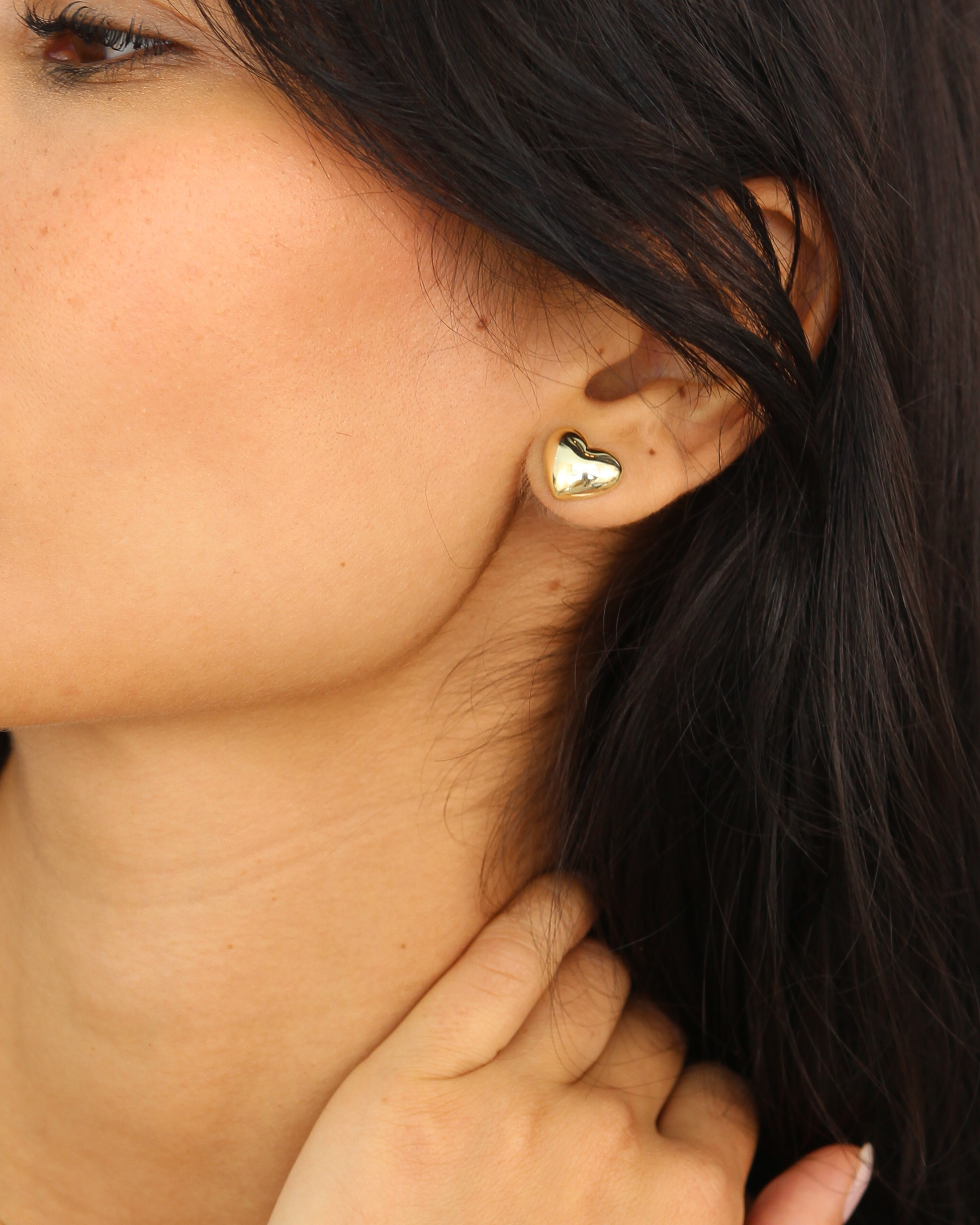 Close-up of a person wearing a gold heart-shaped earring.