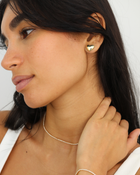 Woman wearing a gold heart-shaped earring on a white background