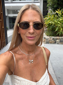 Woman wearing sunglasses and a white top outdoors